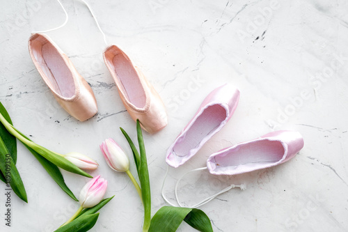 Ballet pointe shoes near spring tulips on white background top view copy space