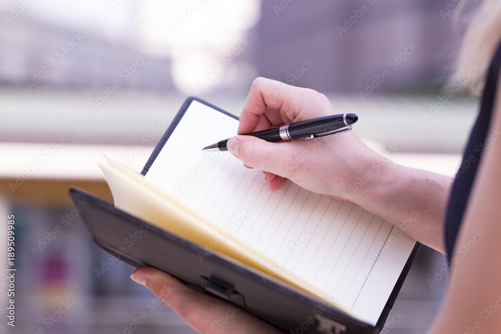Obraz premium Closeup Of Beautiful Businesswoman Holding A Blank Note Book And Right With Luxury Pen Ready To Write.