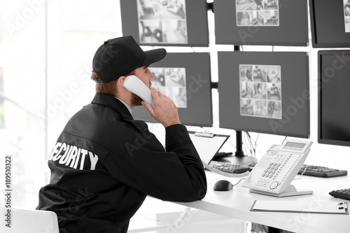Male security guard talking by telephone in surveillance room