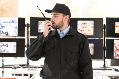 Canvas Print Male security guard using radio transmitter in surveillance room