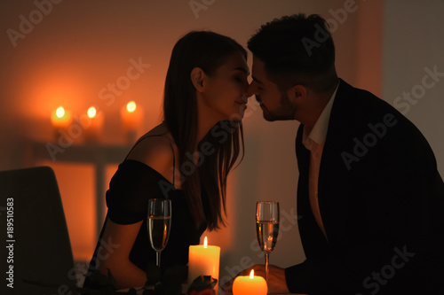Young couple kissing while sitting at table with burning candles