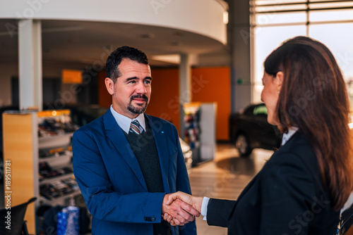 Mature businessman shaking hands with car dealer.