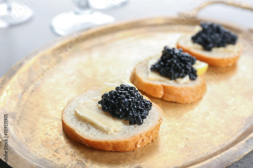 Tasty sandwiches with black caviar on metal tray