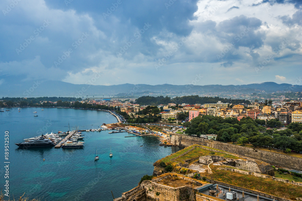 Aerial scenic view on old fortress in Corfu, historical part of city and parked boats and yachts on Ionian sea. Greece.