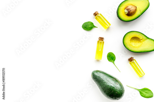 Natural products for skin care. Avocado oil in bottles near sliced avocado on white background top view copy space