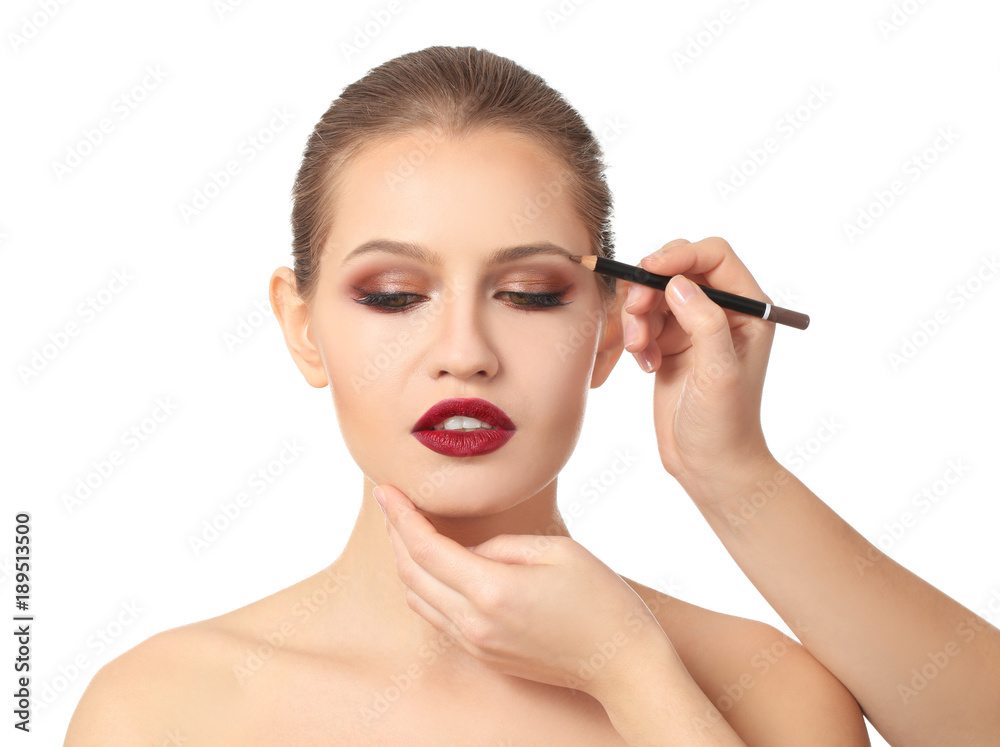 Professional visage artist applying makeup on woman's face on white background