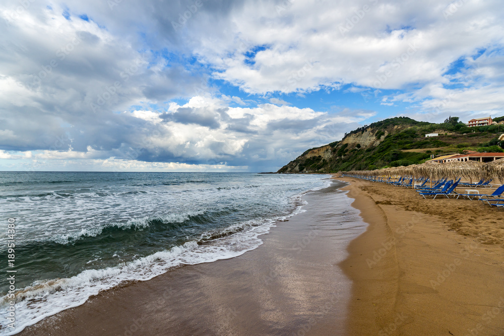 Sand beach, loungers and umbrellas on the shore of Ionian sea, Corfu, Greece.
