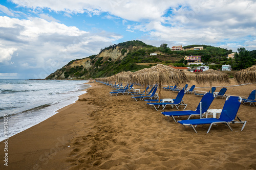 Sand beach, loungers and umbrellas on the shore of Ionian sea, Corfu, Greece. © Media_Works
