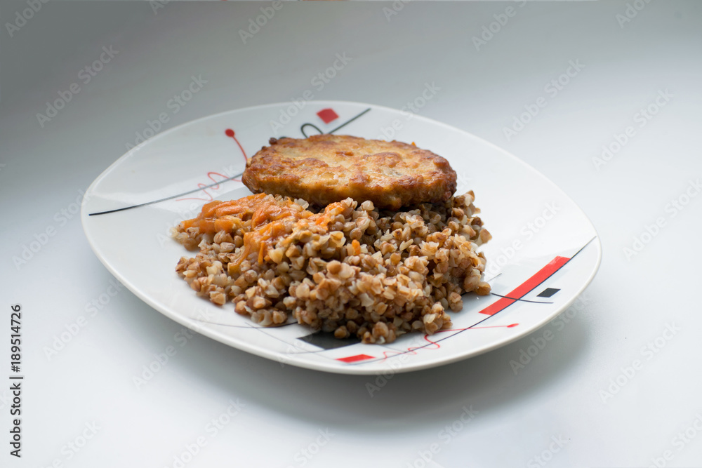 buckwheat porridge with a cutlet on a white plate. Buckwheat cereal with schnitzel. buckwheat porridge with a cutlet on a white plate. Buckwheat cereal with schnitzel.