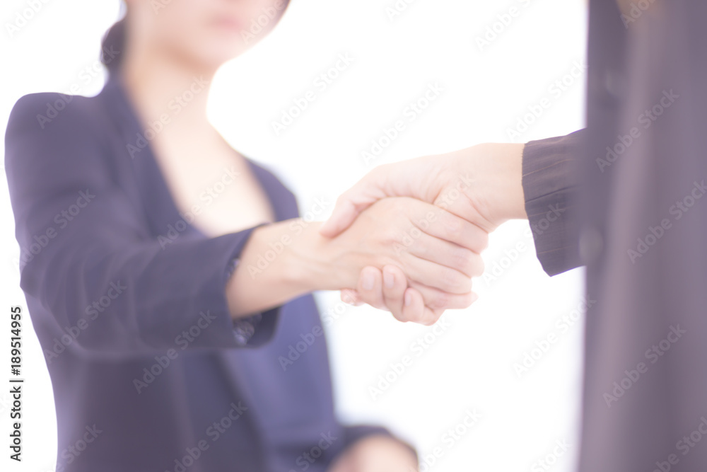 Asian Businesswomen handshake, dark blue and blurred background.