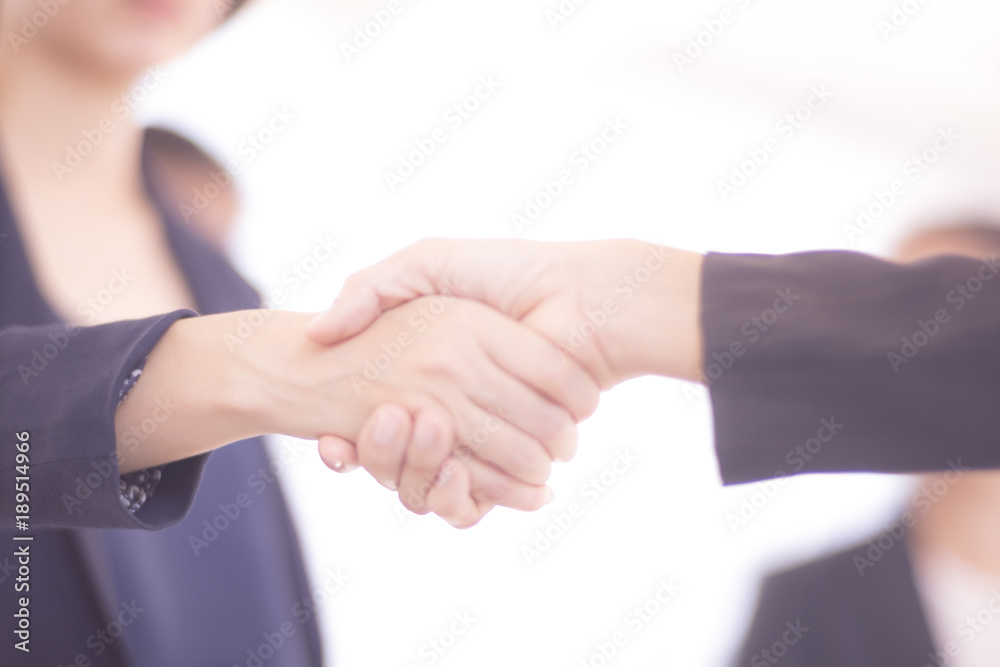 Asian Businesswomen handshake, dark blue and blurred background.