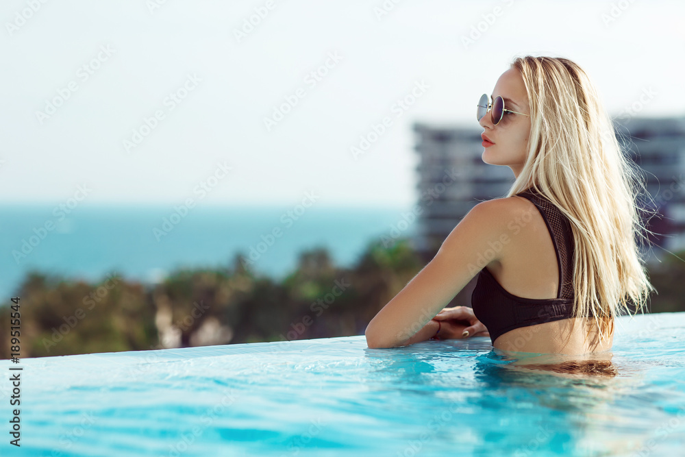 Young model woman in black bikini in a swimming pool