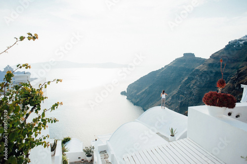 The girl is standing on the roof and looking at the sea on the island of Santorini