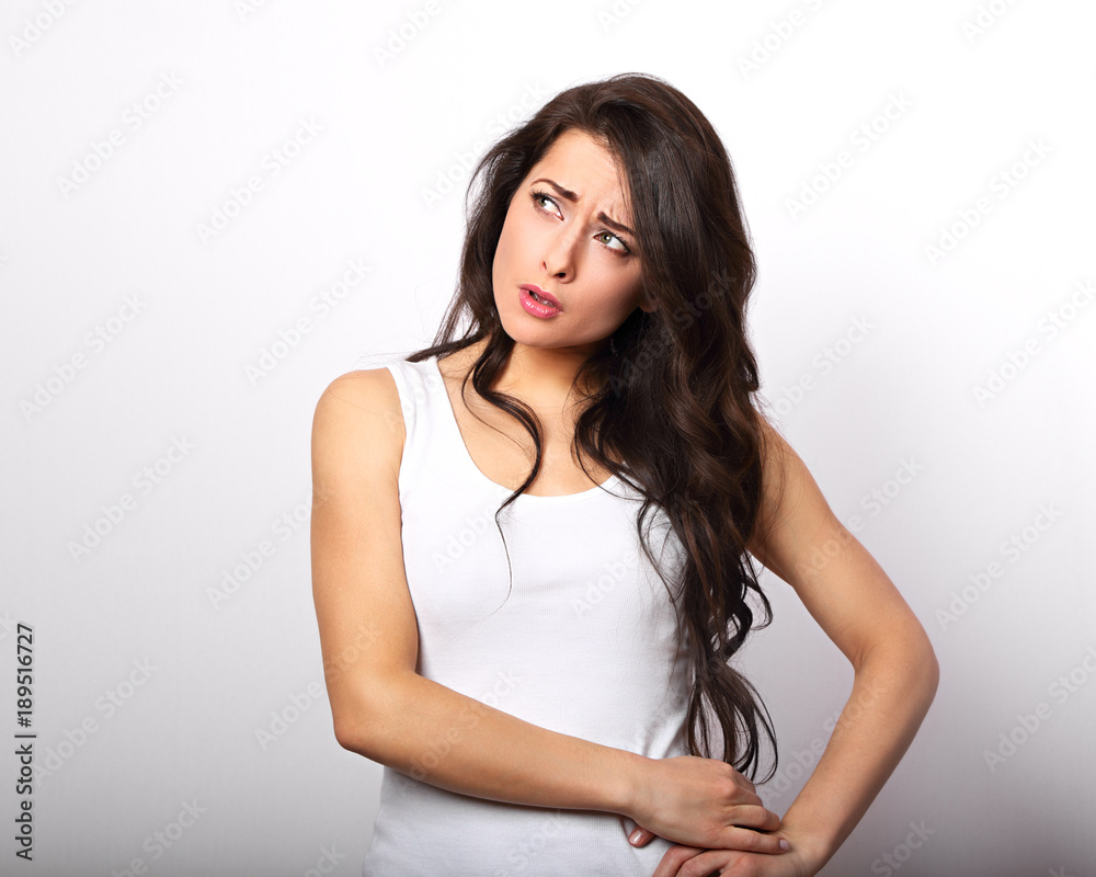 Confusion unhappy brunette woman thinking and scratching the head in white t-shirt on white background Confusion unhappy brunette woman thinking and scratching the head in white t-shirt on white background