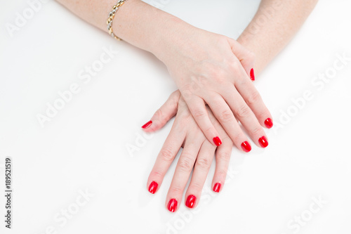 Female hands with manicure and red lacquer on a white table in the beauty salon. closeup of hand of a young woman.
