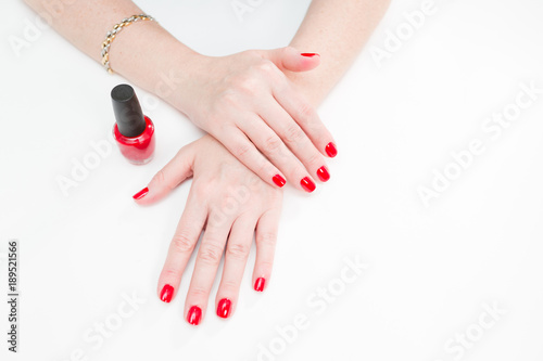 Bild auf Leinwand Female hands with manicure and red lacquer on a white table in the beauty salon