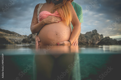 mujer embarazada bañandose en el mar con su pareja