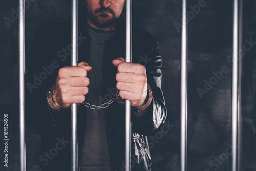 Handcuffed man behind prison bars