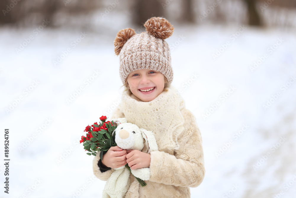 Portrait of a cute girl with a soft toy and a bouquet of flowers for a walk in the winter