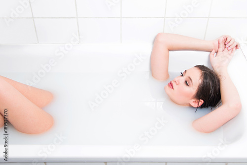 Beautiful young nude girl relaxing and enjoying in bath  white milk cream 