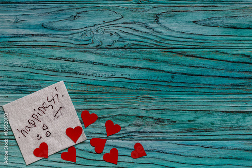 On a wooden background there are small hearts beside a napkin with a wish. Valentine's day concept. photo