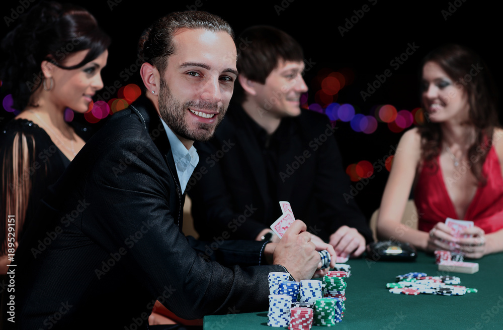Poker players sitting around a table at a casino. Poker players sitting around a table at a casino.