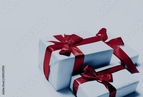 White gifts with red ribbon bow, isolated on white.