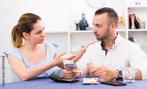 Young female and her husband are counting finance at the table
