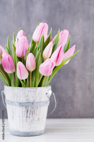 Spring easter tulips in bucket on white vintage background.