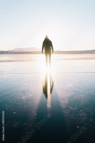 Man walks with his reflection following on a frozen lake in the Golden Circle in Iceland