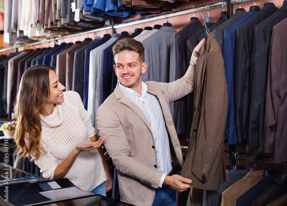 Couple deciding on new suit in men’s cloths store