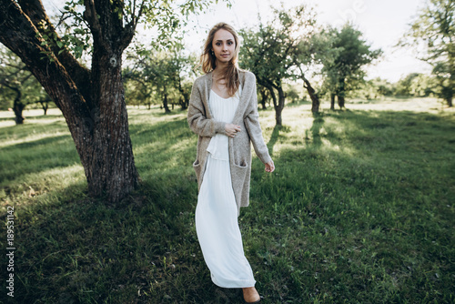 Charming girl in white dress walking in the garden