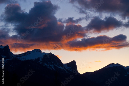 Silhouetted mountains orange sunset clouds 