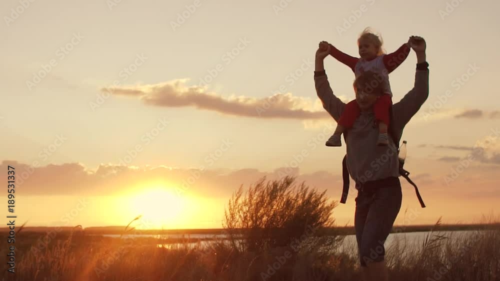 Dad plays with daughter at sunset. Daughter on shoulders of father. Slow motion Dad plays with daughter at sunset. Daughter on shoulders of father. Slow motion