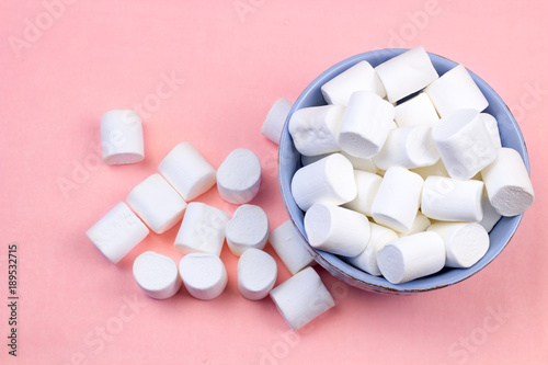 Marshmallows in blue plate on pastel pink background.