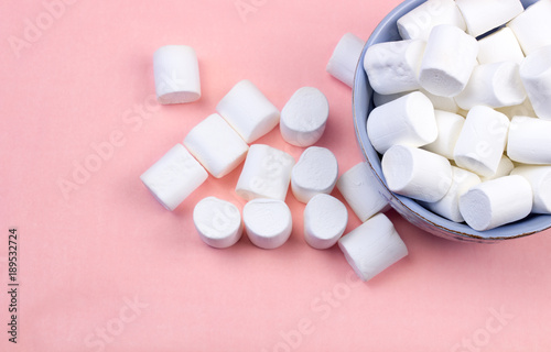 Marshmallows in blue plate on pastel pink background.