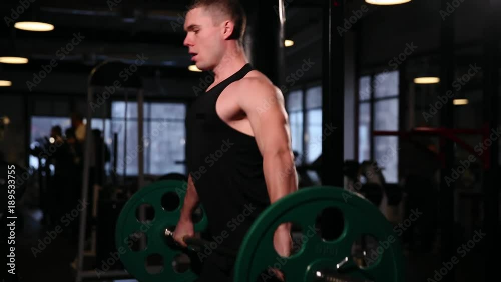 A sports athlete in the gym raises the bar with a weight above his head from the sitting position. close-up camera moves from bottom to top. A sports athlete in the gym raises the bar with a weight above his head from the sitting position. close-up camera moves from bottom to top.