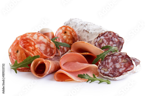 Mixed air cured sliced meats isolated on white. Rocket garnish.