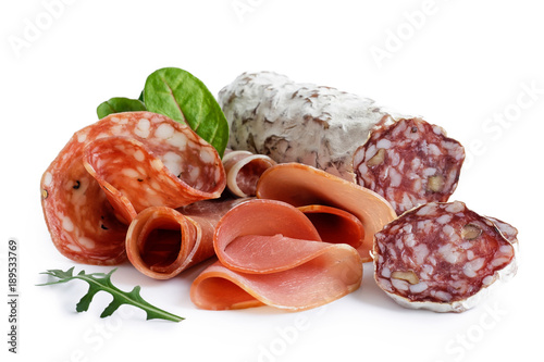 Mixed air cured sliced meats isolated on white. Green leaves.