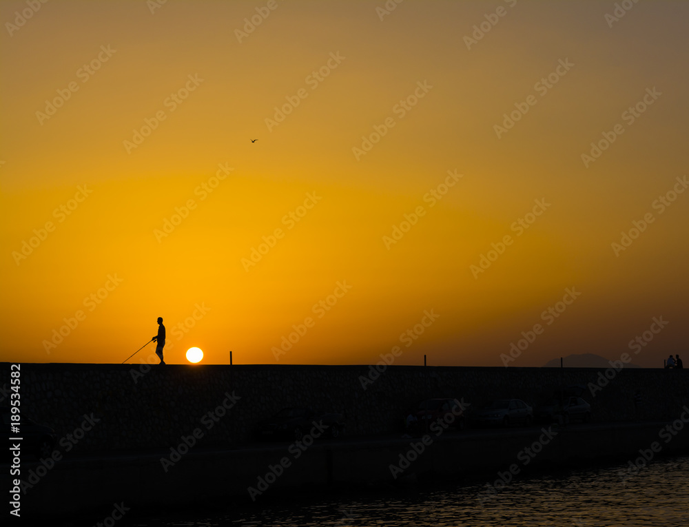 Fisherman at sunset in Alimos marina in Athens, Greece