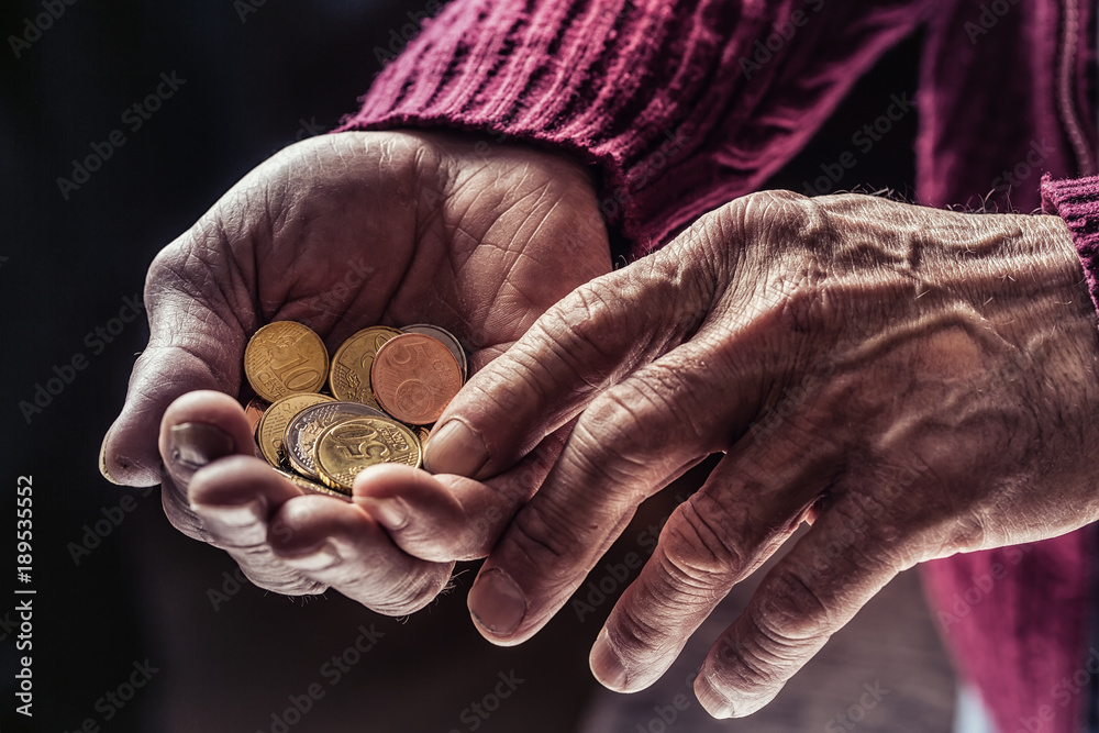 Pensioner man holding in hands euro coins. Theme of low pensions. - obrazy, fototapety, plakaty 
