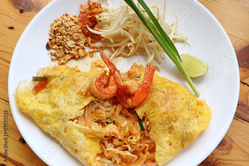 Thai Style Fried Egg Wrapped Stir Fried Noodle or Pad Thai Topped with Shrimps Served on White Plate 