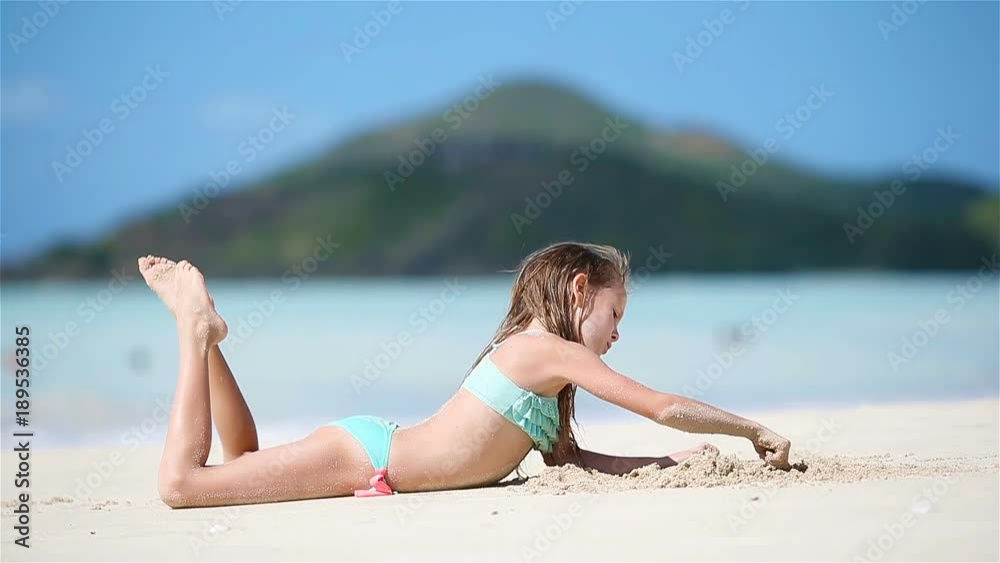 Adorable little girl at beach having a lot of fun in shallow water Adorable little girl at beach having a lot of fun in shallow water