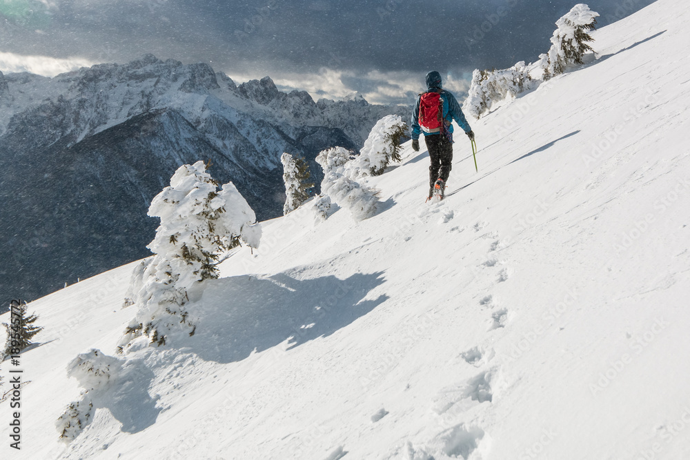 Mountaineer walking on the snowy slope of theDovska Baba mountain in Karavanke range in a wind, Slovenia