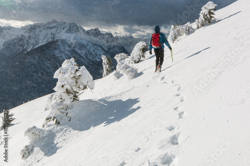 Mountaineer walking on the snowy slope of theDovska Baba mountain in Karavanke range in a wind, Slovenia