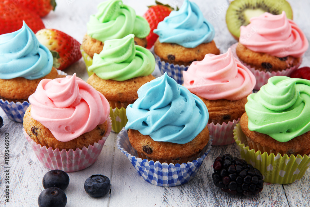 Tasty cupcakes on wooden background. Birthday cupcake in rainbow colors