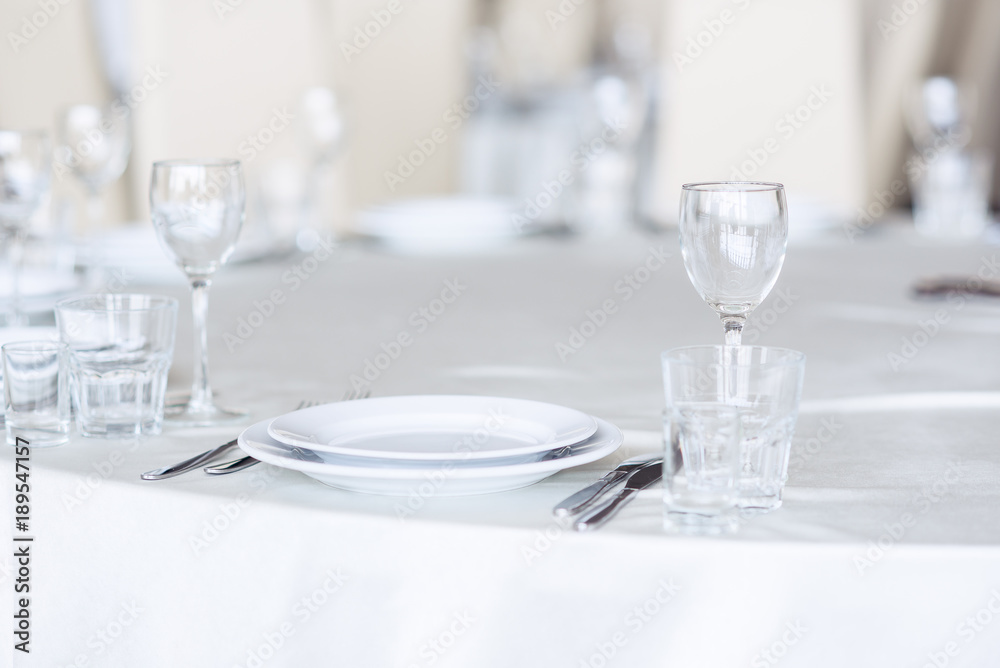 Sparkling glassware stands on round table prepared for holiday dinner. Champagne glasses on the celebration table. Sparkling glassware stands on round table prepared for holiday dinner. Champagne glasses on the celebration table.
