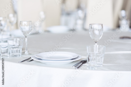 Sparkling glassware stands on round table prepared for holiday dinner. Champagne glasses on the celebration table.