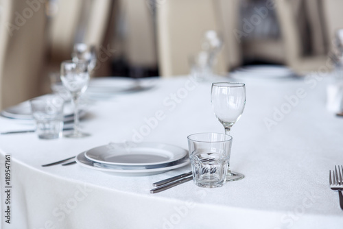 Sparkling glassware stands on round table prepared for holiday dinner. Champagne glasses on the celebration table.