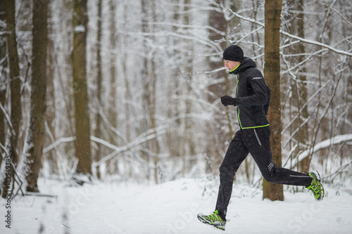Photo from side of man in sports clothes on run in winter